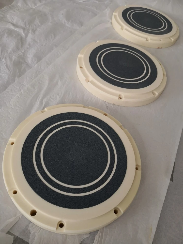 Composite circular ceramic vacuum chuck with a 99 percent alumina base, dark porous silicon carbide vacuum surface and dense ceramic separator rings.